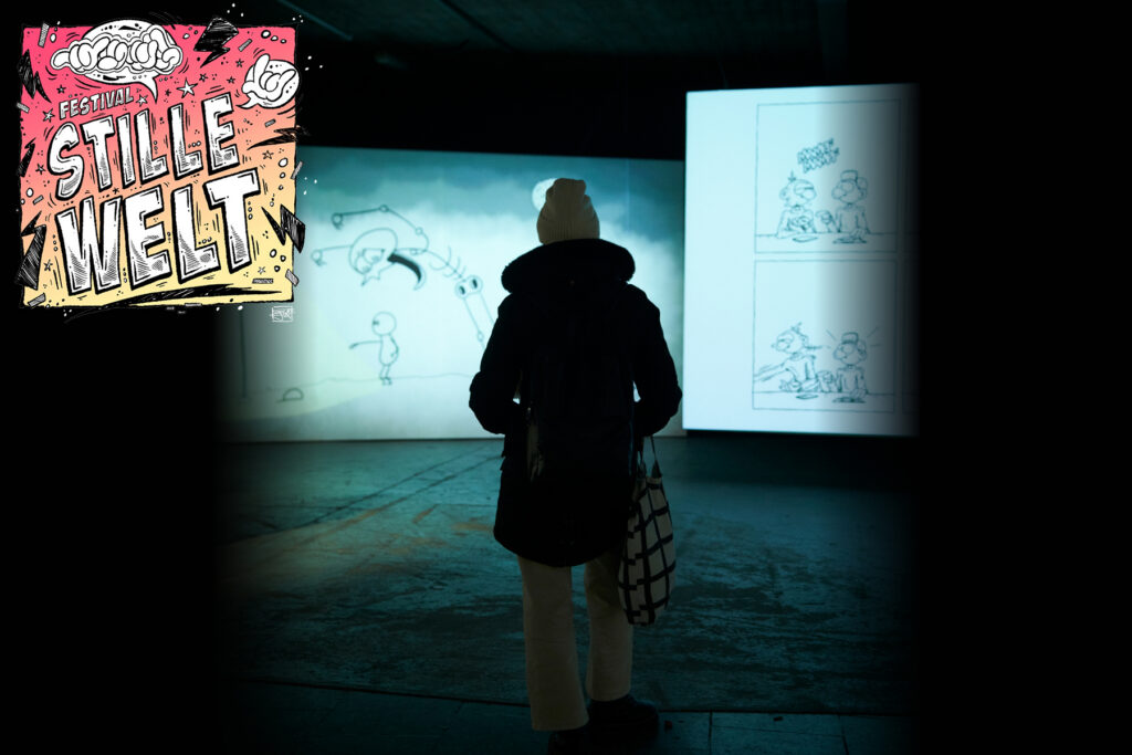 Eine Person steht in einem dunklen Ausstellungsbereich und schaut sich Animationen an.